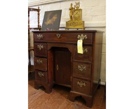 A George II mahogany kneehole desk with shaped top, one central drawer under with four smaller with brass drop handles, carve