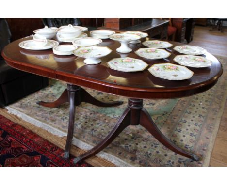 A Regency-style 'D' end mahogany dining table with string inlay to the shaped top, raised on twin pedestal supports on tripod