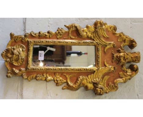A 19th century French gilt wall mirror with oblong plate with profusely carved surround depicting cherubs, masks and 'C' scro