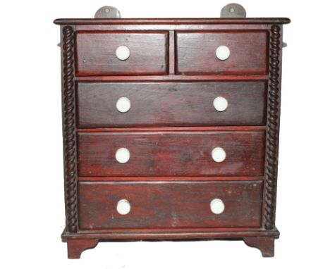 A Victorian oak stained miniature chest of two small and three graduated drawers with shaped top, circular porcelain handles,
