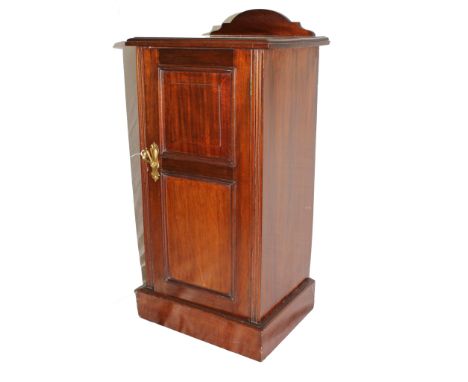 An Edwardian mahogany bedside locker with domed tray back, single panelled door with brass drop handle, fluted supports, inte