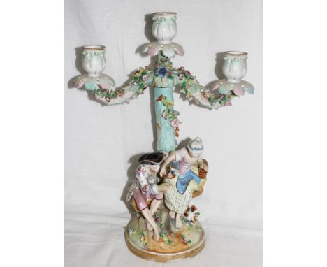 An early 20th century Meissen-style ceramic two branch candelabra with a seated lady and gent to the circular base, 34cm high