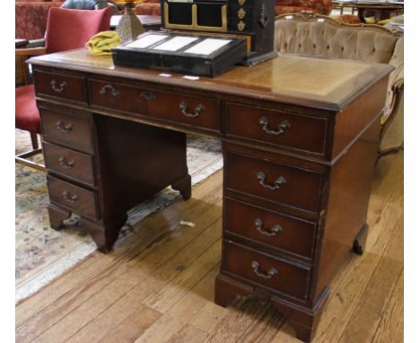 A Georgian-style twin pedestal desk with tooled leather inset, shaped top, eight small and one central drawer with brass drop