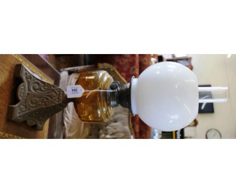 An Arts and Crafts oil lamp with circular milk glass shade, chimney on a carved stylized square base, 60cm high