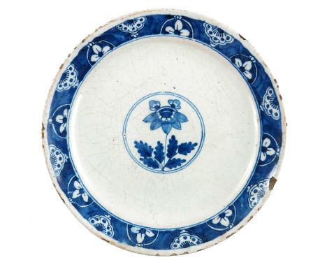 A Delft blue and white plate, circa 1760, central floral sprig within a double concentric ring, bordered in floral and rosett