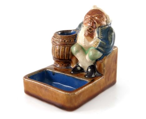 Harry Simeon for Doulton Lambeth, a stoneware match striker, modelled as a seated Toby next to a barrel, the reverse with str