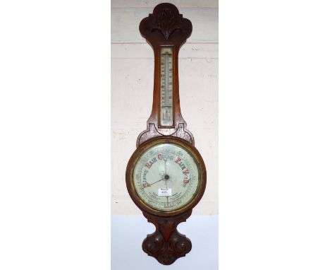 An Edwardian carved oak aneroid barometer with thermometer