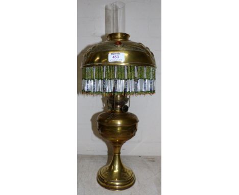An Art Nouveau embossed brass oil lamp with jewelled and tasselled shade