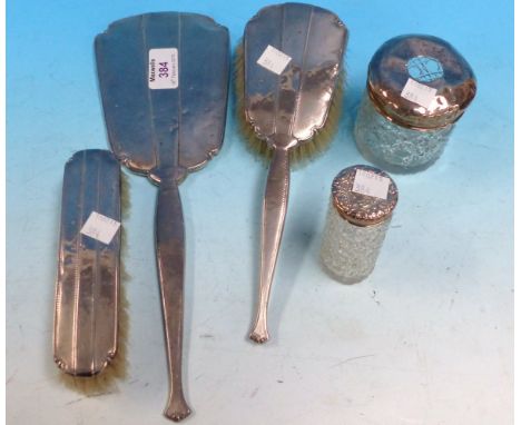 A silver and floral enamel back hand mirror (unmarked); an engine turned 3 piece dressing table set; 2 silver top toilet bott