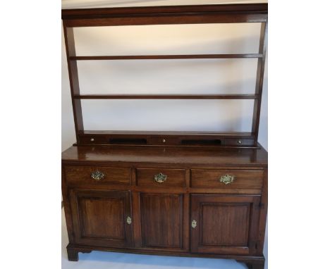 Geo.III oak dresser, three drawers above a pair of fielded panel doors, with panelled sides on shaped bracket feet W150cm D49