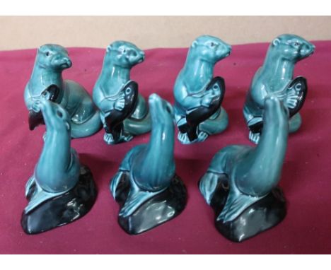 Poole Pottery four otters holding fish figurines, and three seals (7) 