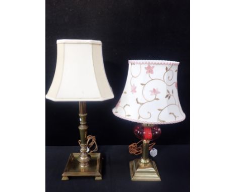 A BRASS OIL LAMP WITH CRANBERRY GLASS RESERVOIRconverted to electricity (font not drilled), and a brass table lamp with squar