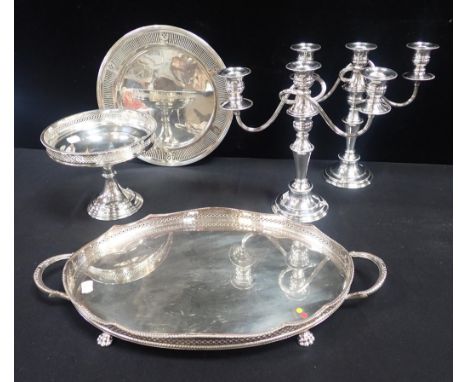 A SILVER-PLATED ON COPPER OVAL GALLERIED TRAYon paw feet, a pair of plated candelabra, a plated bread plate, and similar comp
