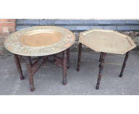 TWO INDIAN BRASS TRAY-TOP TABLESwith folding stands, the largest with repousse hunting scene border 77cm dia (2)