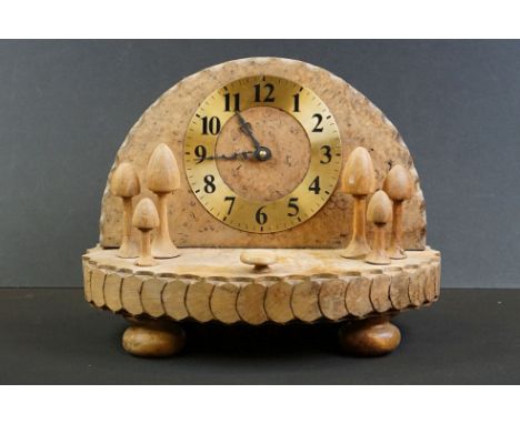 Carved burr wood toadstool clock with Arabic numerals on a brass dial, cog-like carved edge rims, raised on four bun feet, in