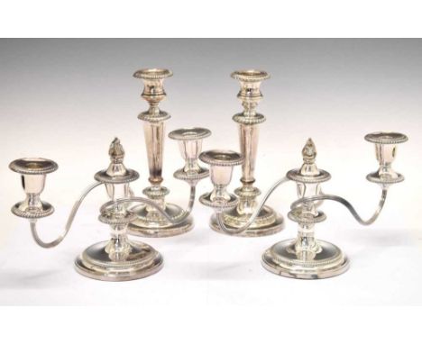 Pair of silver-plated three-light candelabra, together with a pair of en-suite candlesticks, 23cm high and smaller