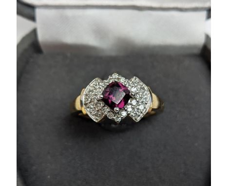 A 9CT GOLD RHODOLITE GARNET SET DRESS RING, the central cushion cut stone of 0.50 carat, surrounded by diamonds, ring size N½