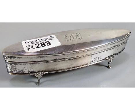 George V silver oval shaped ring box on four shaped feet with engraved initials. Rubbed hallmarks for London.  (B.P. 21% + VA