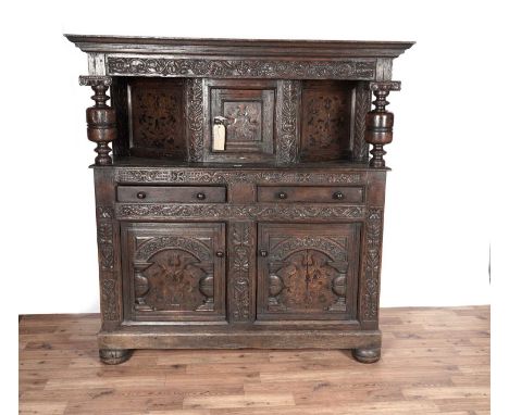 A substantial 17th Century style inlaid oak court cupboard with moulded ogee cornice and carved frieze, above cupboard flanke
