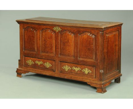 A Georgian oak Lancashire mule chest, with lift up top and four panelled front with two drawers beneath with brass drop handl