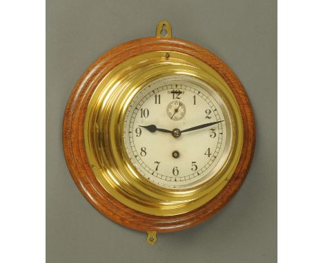 A brass cased ships clock, with subsidiary seconds dial, mounted on an oak plaque stamped verso "2853".  Plaque diameter 26 c