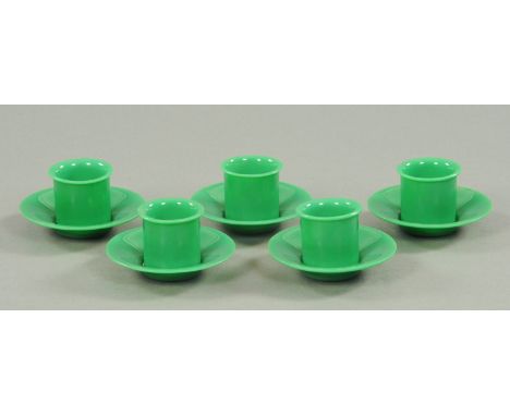 A set of five jade green Peking glass cups and saucers, late 19th/early 20th century, the cups of cylindrical form with evert