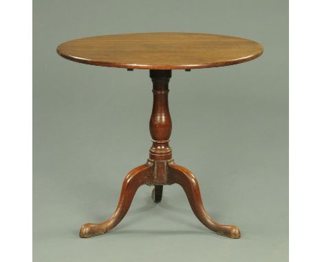 A George III oak tripod occasional table, with snap action, turned column and three downswept legs terminating in pad feet.  