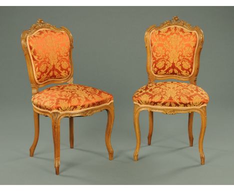 A pair of French side chairs, walnut, with exposed scroll carved showframes, upholstered backs, stuffover seats and raised on