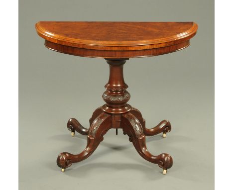 A Victorian walnut demi-lune turnover top card table, raised on a turned column and with four downswept legs terminating in s