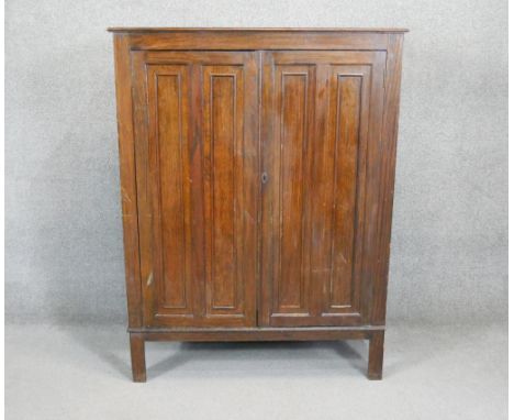 A mid century vintage oak wardrobe with panel doors enclosing fitted interior on square supports. H.140 W.107 D.42 CM 