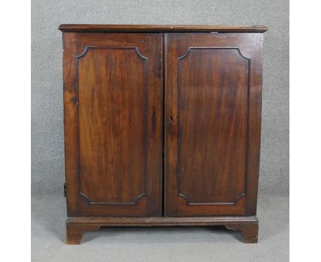 A Georgian mahogany side cabinet with panel doors enclosing open space on bracket feet. H.107 W.96 D.59cm (One hinge detached