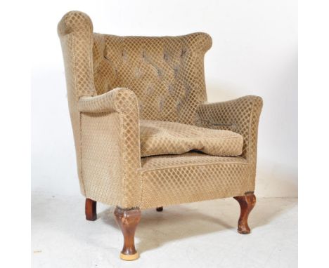 A 1930s Queen Anne revival wing back arm chair. The chair having a rounded upright backrest with button back upholstery and s