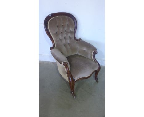 A Victorian mahogany framed spoon back armchair with fabric button back upholstery, serpentine fronted seat on C scroll and s