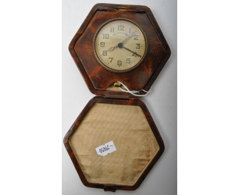 An Art Deco travel leather cased clock. In hexagonal form with a leather case that folds closed inset with pocket watch. With