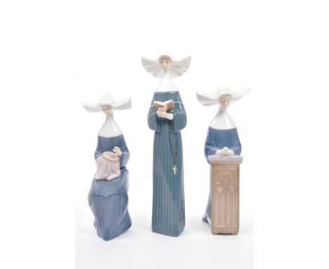 An assortment of three vintage 20th century Spanish Lladro bone china figures of nuns. The lot to include a standing reading 