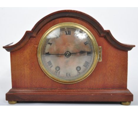 A vintage early 20th Century wood mantel clock. With a rectangular shaped, curved sloping top, with a metal face and ebonised