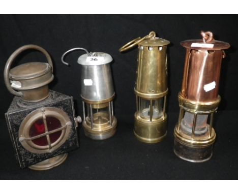 A brass miner's lamp, another similar and a hand held brass and japanned tin oil lamp with a red lens (4)