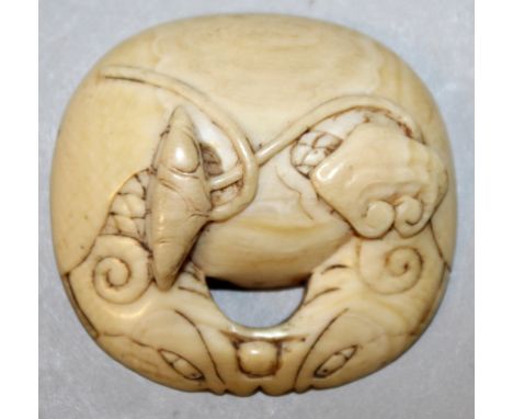 A SMALL JAPANESE MEIJI PERIOD IVORY NETSUKE, rendered as one half of a temple bell, each side carved in relief with lotus, 1.