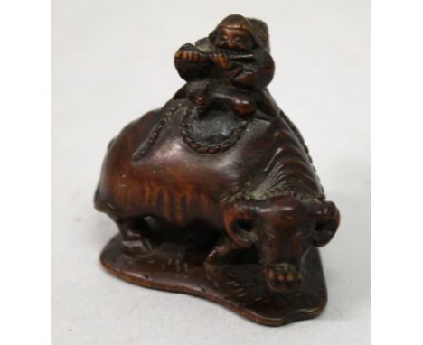 A GOOD QUALITY SIGNED JAPANESE MEIJI PERIOD BOXWOOD NETSUKE OF A BOY SEATED ON A WATER BUFFALO, the boy playing a flute and w