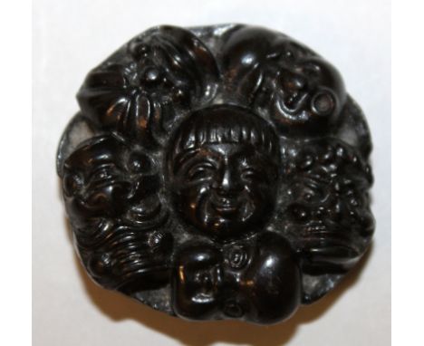A JAPANESE WOOD NOH MULTIPLE MASK NETSUKE, the flattened circular form modelled in relief with various Noh masks, 1.75in diam