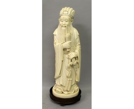 A GOOD LARGE CHINESE IVORY FIGURE OF A SAGE, the ivory weighing 1.74Kg, together with an oval wood stand, the sage dressed in