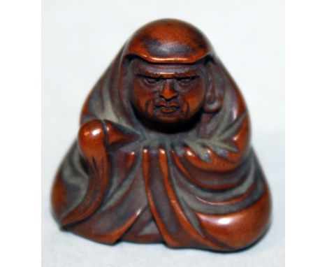 A SIGNED JAPANESE MEIJI PERIOD WOOD NETSUKE OF DARUMA, seated in flowing robes and holding a fly whisk, the reverse with an e