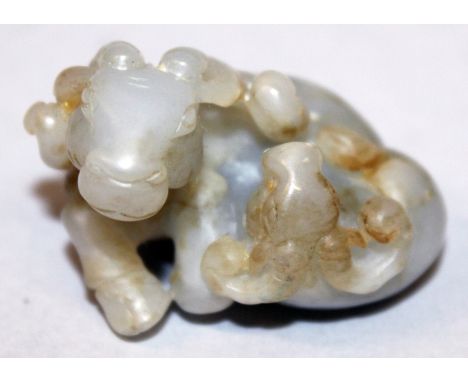A CHINESE GREY & WHITE JADE MODEL OF A SEATED RAM, in the company of its young, the stone with russet inclusions, 1.75in wide
