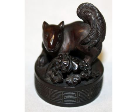 AN UNUSUAL JAPANESE WOOD MEIJI PERIOD SEAL NETSUKE, with applied silver-metal himotoshi, carved in the form of a squirrel sta