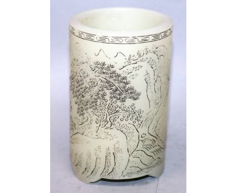 A CHINESE CELADON JADE-LIKE GLASS BRUSH POT, supported on three bracket feet, the sides stained and engraved with calligraphy