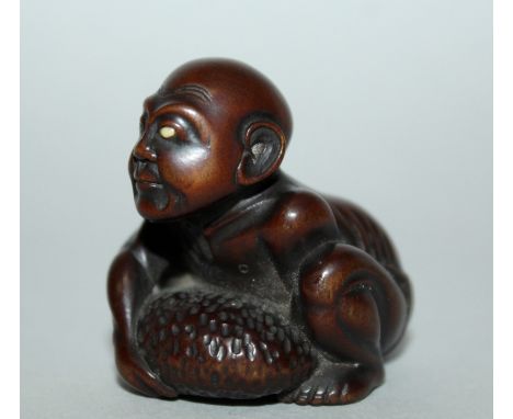 A GOOD JAPANESE MEIJI PERIOD CARVED WOOD NETSUKE OF A BLIND MASSEUR BY GYOKKEI, the man crouching and lifting a strength ston