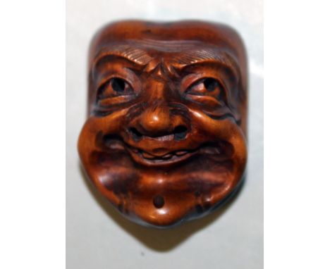 A JAPANESE MEIJI PERIOD WOOD NOH MASK NETSUKE, of a man with smiling features and pronounced eyebrows, 1.4in high x 1.1in wid