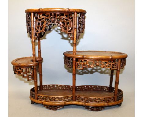A CHINESE TIERED WOOD DISPLAY STAND, with pierced key-fret friezes, borders and feet, 18.3in wide & 15in high.