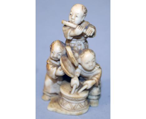 A SIGNED JAPANESE MEIJI PERIOD NETSUKE OF A GROUP OF BOY MUSICIANS, playing various instruments, one of the three boys standi