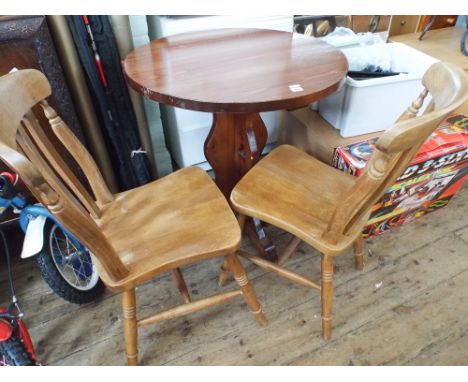 A circular pub style table with 2 stick back chairs 